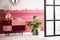 Green pant in concrete pot next to commode with flowers in vase, books and clock