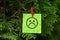 Green paper note with a sad face hanging on a tree