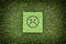 Green paper with sad unhappy face on a green grass