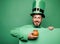 Green patricks background. Man in Patrick`s suit smiling. Man in Saint Patrick`s Day leprechaun party hat having fun on