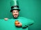 Green patricks background. Man in Patrick`s suit smiling. Man in Saint Patrick`s Day leprechaun party hat having fun on