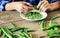 Green peas bowl wooden table Female hands clean green peas sitting wooden table kitchen close up Rustic style