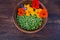 Green peas and colorful edible flowers in clay bowl