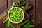 Green peas in pods and peeled in wooden bowl on table