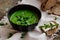 Green peas and spinach puree soup in a black bowl. Vegetarian cream soup on gray background. Healthy eating during quarantine