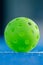 green pickleball on blue background