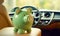 Green piggy bank in the car interior. The concept of purchasing, credit, leasing or car insurance