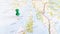 A green pin stuck in the island of colonsay on a map of Scotland
