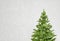 Green pine tree toy model with falling white snow in grey background.