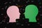 green and pink paper heads looking at each other on a black background with abstract beads