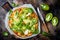 Green pizza with pesto, zucchini, tomatoes, avocado, jalapeno, mozzarella cheese and fresh basil.