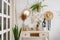 Green plants, dried flowers and cactuses on a table in rustic style. Cozy loft interior with white brick wall