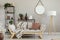 Green plants in pots, candles and books on metal shelves in beige scandinavian living room