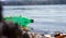 A green plastic bottle floats down the river. The river is very polluted and the bottle should be recycled