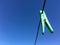 Green plastic clothespin clothes peg hanging from wire laundry line outdoors