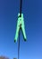 Green plastic clothespin clothes peg hanging from wire laundry line outdoors