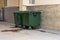 Green plastic garbage containers installed along in the yard of the house. The concept of separate garbage collection