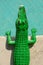 Green plastic toy crocodile on a swimming pool side