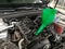 Green plastic watering can in the oil filler neck of a car engine.  Oil change.