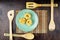 Green plate with fettuccine paste on a bamboo napkin and wooden spatulas on a mahogany background