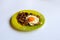 Green plate with fried egg and onion on a light background.
