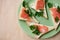 Green plate with salmon sandwiches with butter and parsley on wooden table. Buffet breakfast lunch meal. Healthy eating. Fish diet