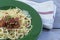 Green plate of Traditional Italian spahgetti Bolognaise or Bolognese with cooked pasta noodles topped with a tomato