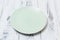Green Plate on white scraped wooden background side view
