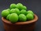 Green plums in a pottery bowl