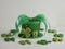 Green polka dot leprechaun hat with green boa and a gold buckle surrounded by green glittery four leaf clover shamrocks on a white