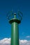 Green position light at the harbor entrance against a blue sky