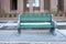 Green public park bench seating metal concert on cement sidewalk