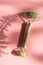 Green quartz Face massage roller and fern leaf on pink table