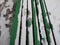 Green railing of a street bench of wood in the snow.