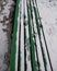 Green railing of a street bench of wood in the snow.