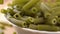 Green raw pea spinach vegetable vegetarian pasta. Falling macaroni on a full white bowl in slow motion. Macro shot.