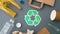 Green recycle symbol with household waste on grey