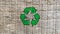 Green recycling icon on a weathered plank