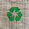 Green recycling icon on weathered wooden board