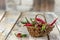 Green and red chili on wicker basket on wood table, of the kitchen background