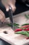 Green and red chilie peppers being cut on a wooden board