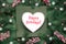 Green red Christmas background with text Happy Holidays on white paper heart. Natural Xmas twigs decorated with frosted