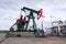 Green and red pumpjack, oil horse, oil derrick pumping oil well with dramatic cloudy sky background