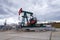 Green and red pumpjack, oil horse, oil derrick pumping oil well with dramatic cloudy sky background