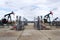 Green and red pumpjack, oil horse, oil derrick pumping oil well with dramatic cloudy sky background