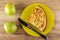 Green ripe apples, piece of apple pie and knife on yellow plate on wooden table. Top view