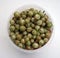 Green ripe gooseberries in white plastic cup on white background