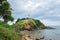 Green rocky cape with a white lighthouse. Tropical seascape. Koh Lanta, Thailand