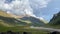 Green rocky slopes of the northern Elbrus region. Blue sky with white clouds. Travelers with a tent.