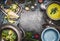 Green Romanesco and broccoli soup with cooking ingredients,kitchen tools, ladle , bowls and spoons on dark rustic background, top